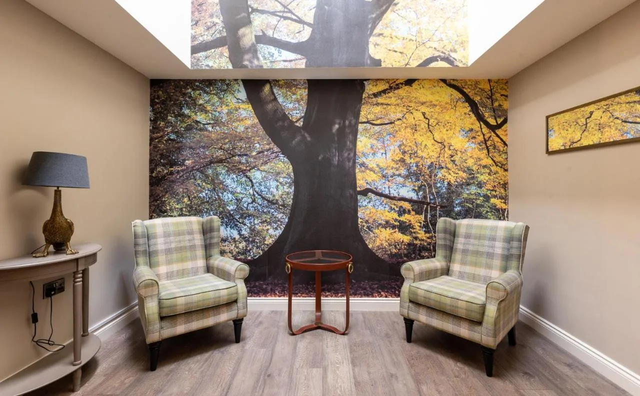 A room with armchairs and a large tree mural at The Lawrance Luxury Aparthotel, York